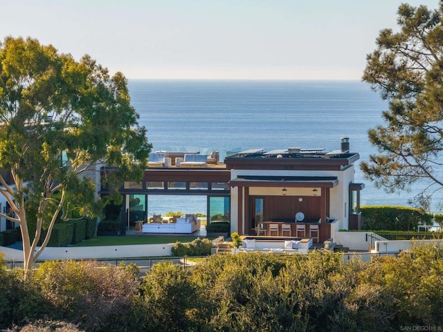 back of property featuring solar panels and a water view