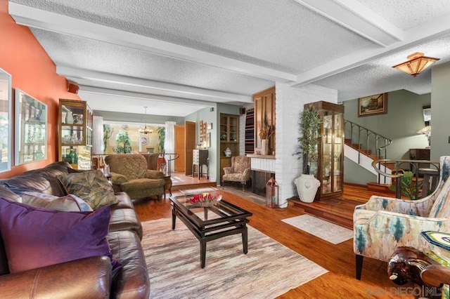 living room featuring a wealth of natural light, light hardwood / wood-style flooring, beamed ceiling, and a textured ceiling