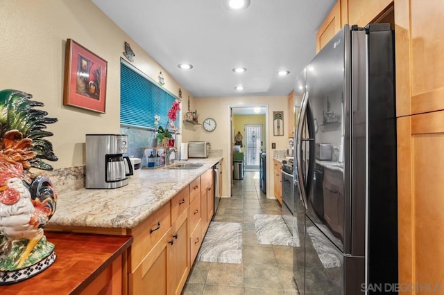 kitchen with light stone countertops, sink, and stainless steel appliances