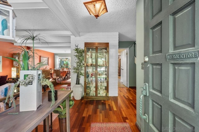 entrance foyer with beamed ceiling, a textured ceiling, and dark wood-type flooring