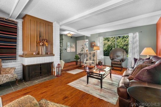 living room with a fireplace, wood-type flooring, a textured ceiling, and beam ceiling