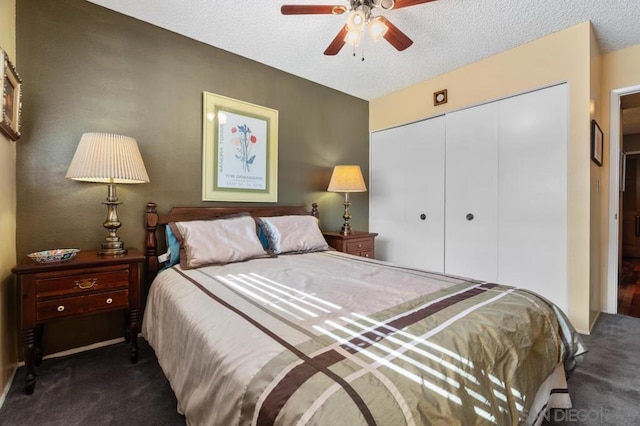 bedroom featuring dark colored carpet, a textured ceiling, a closet, and ceiling fan