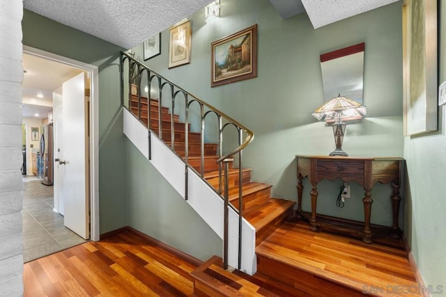 stairs featuring hardwood / wood-style floors and a textured ceiling