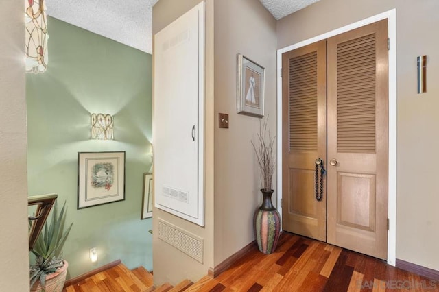 hall with dark hardwood / wood-style flooring and a textured ceiling