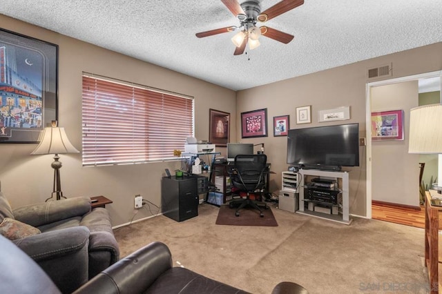 carpeted office space featuring ceiling fan and a textured ceiling