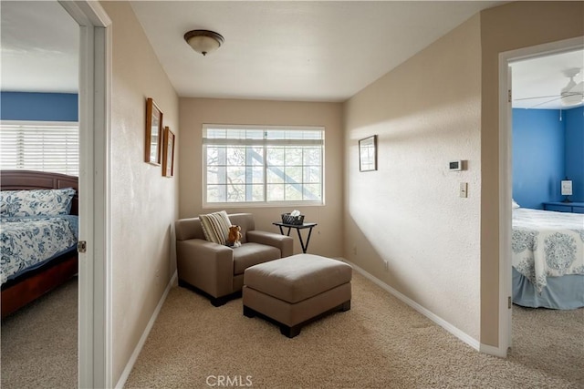 living area featuring ceiling fan, light carpet, and a wealth of natural light