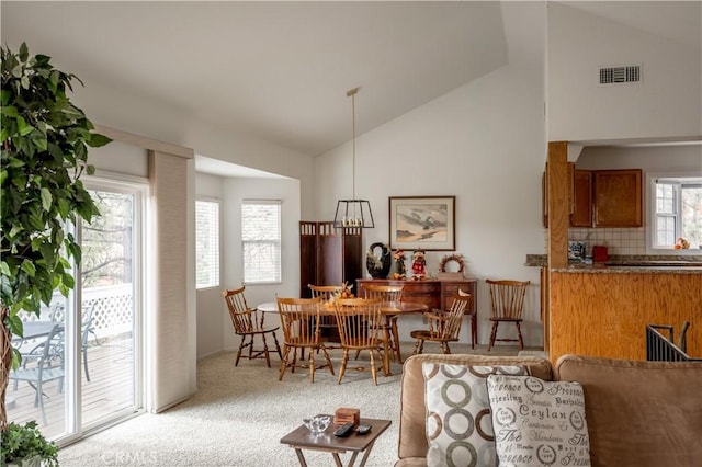 carpeted dining area featuring high vaulted ceiling