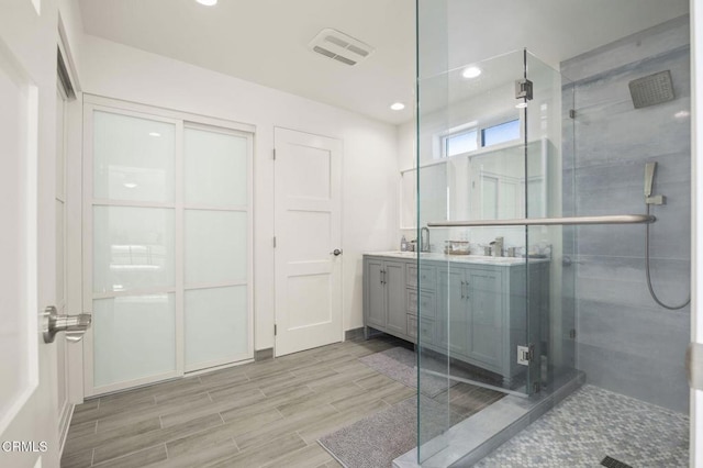 bathroom with hardwood / wood-style floors, vanity, and walk in shower