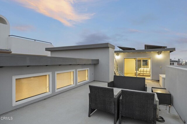 patio terrace at dusk with an outdoor living space and a balcony