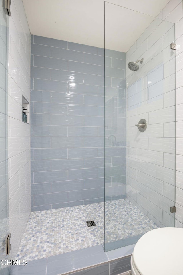 bathroom featuring tiled shower and toilet