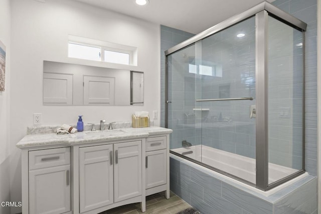 bathroom featuring hardwood / wood-style floors, vanity, and shower / bath combination with glass door