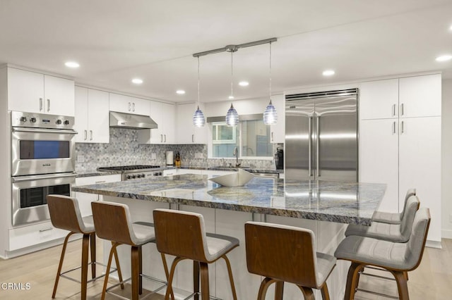 kitchen featuring a center island, stainless steel appliances, dark stone counters, and light hardwood / wood-style floors