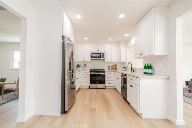 kitchen featuring white cabinetry, sink, light wood-type flooring, and appliances with stainless steel finishes