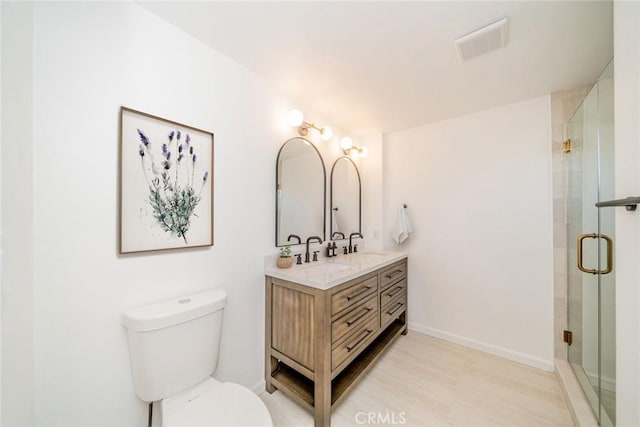 bathroom with vanity, toilet, and a shower with door