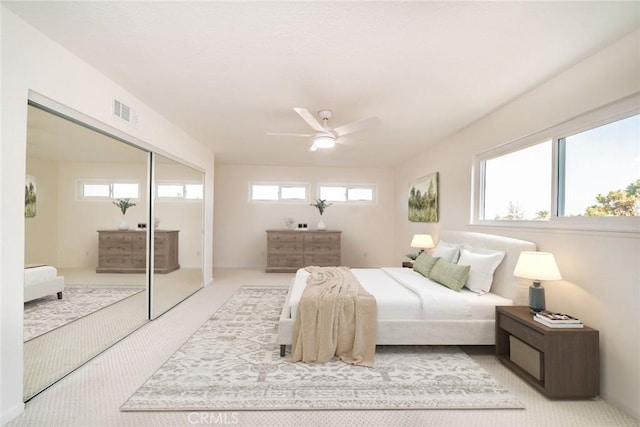 bedroom with ceiling fan, light colored carpet, and a closet