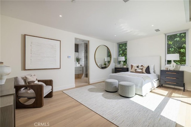 bedroom featuring light wood-type flooring and ensuite bath