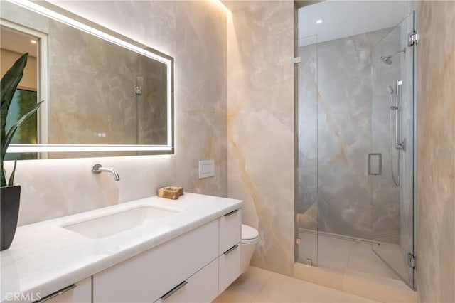 bathroom with tile patterned flooring, vanity, a shower with shower door, and toilet