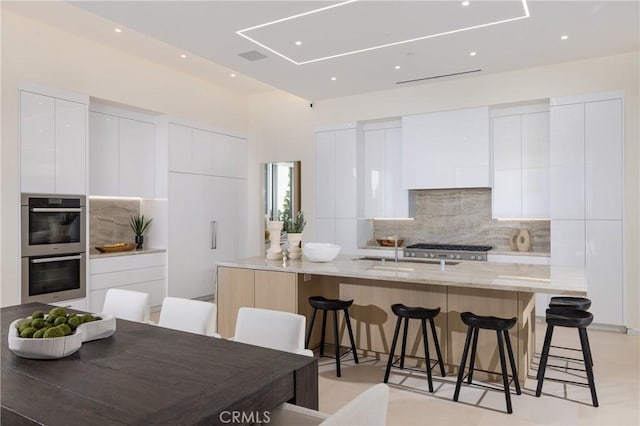 kitchen with white cabinets, a kitchen bar, and light stone counters