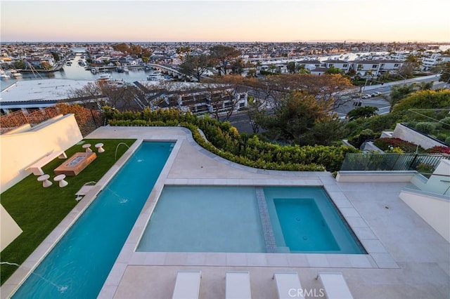 pool at dusk featuring a water view