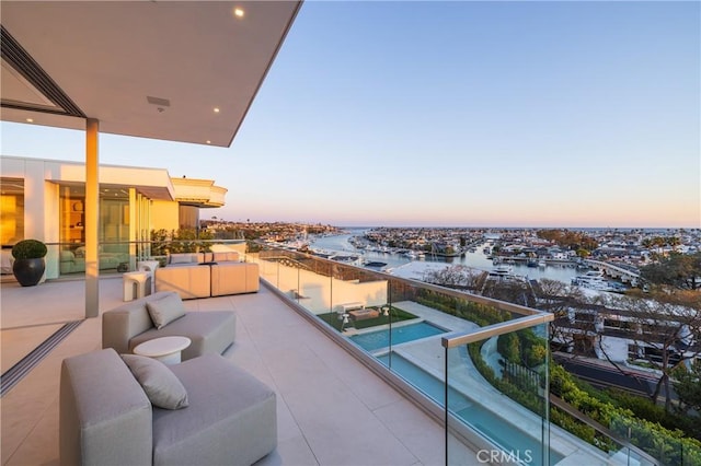 balcony at dusk featuring an outdoor living space and a water view