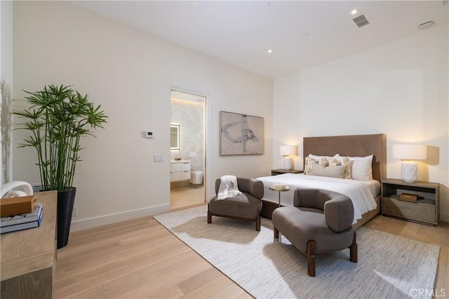 bedroom featuring ensuite bath and light hardwood / wood-style flooring