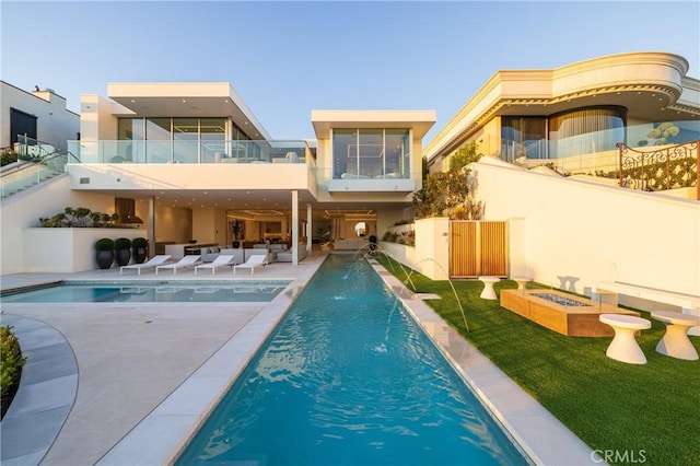 back of property with a patio, a balcony, pool water feature, and a fire pit