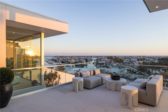 balcony at dusk with an outdoor hangout area and a water view