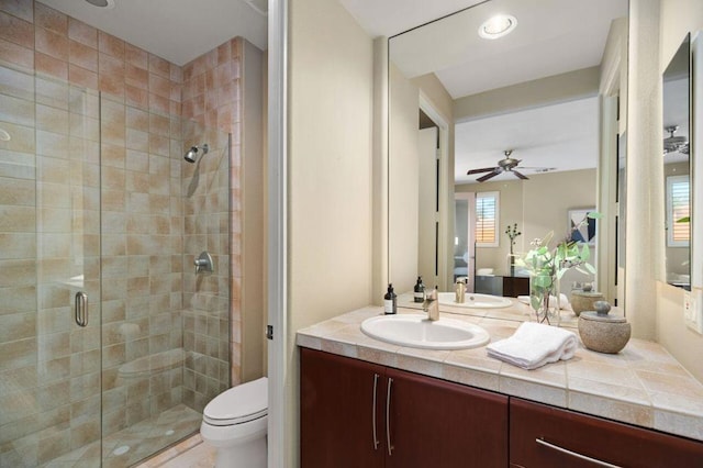 bathroom featuring ceiling fan, plenty of natural light, toilet, vanity, and a shower with shower door