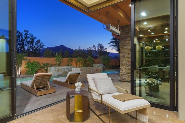 patio terrace at dusk with pool water feature, a mountain view, and a fenced in pool