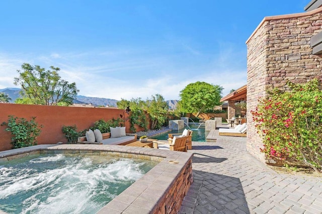 view of patio / terrace featuring a mountain view, pool water feature, and an outdoor hot tub