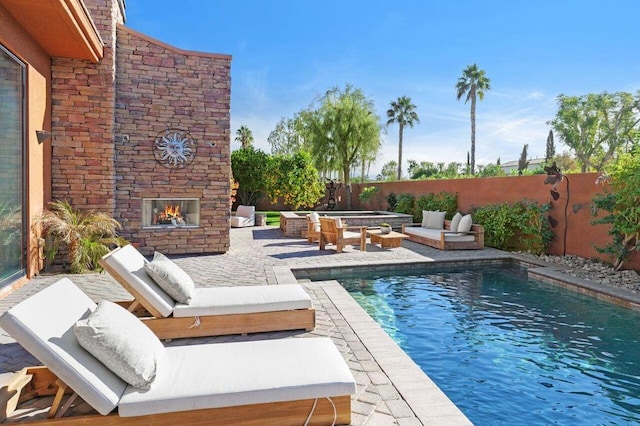 view of pool with an outdoor stone fireplace and a patio