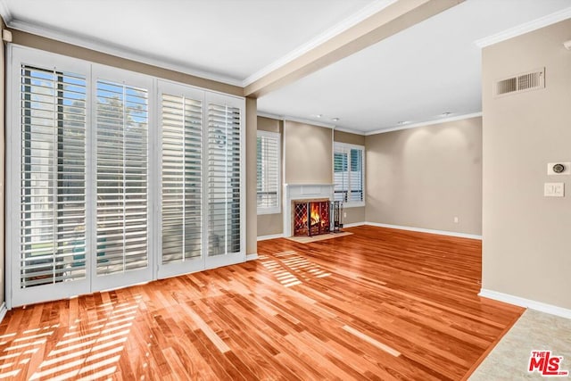 unfurnished living room with ornamental molding, hardwood / wood-style flooring, and a healthy amount of sunlight