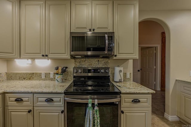 kitchen with cream cabinets, electric range oven, and light stone counters