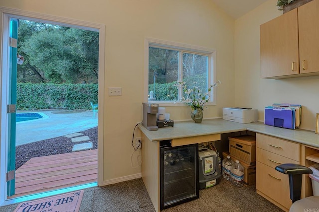 kitchen featuring wine cooler, lofted ceiling, carpet, and light brown cabinets