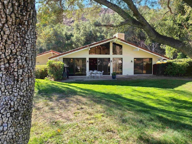 back of property with a patio area and a lawn