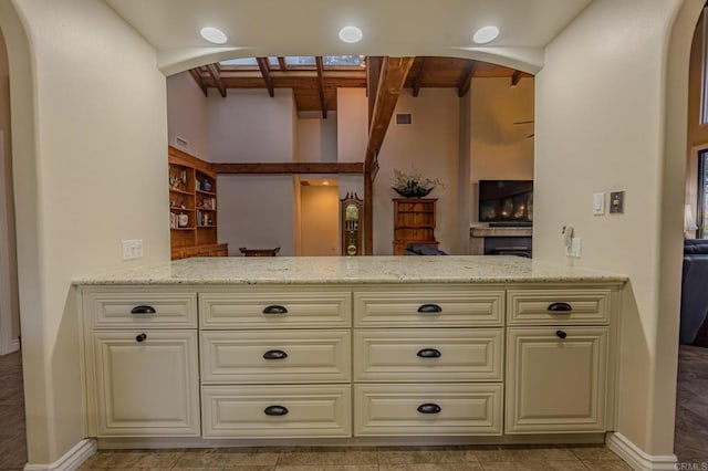 kitchen with beam ceiling, light stone countertops, and kitchen peninsula