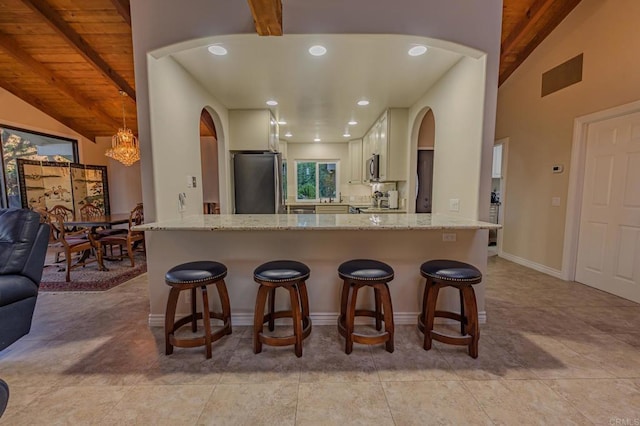 kitchen with appliances with stainless steel finishes, a kitchen breakfast bar, kitchen peninsula, and white cabinets