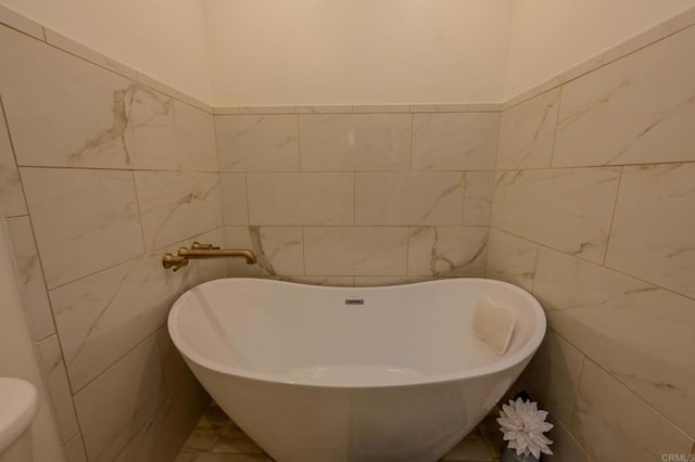 bathroom featuring a tub, tile walls, and toilet