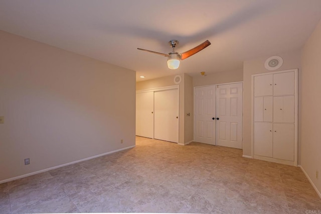 unfurnished bedroom featuring multiple closets and ceiling fan