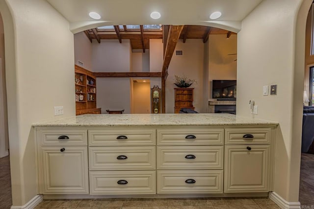 32202 Taupa Way, Pauma Valley, CA 92061 - kitchen with cream cabinetry, arched walkways, light stone counters, wood ceiling with exposed beams, and a high ceiling