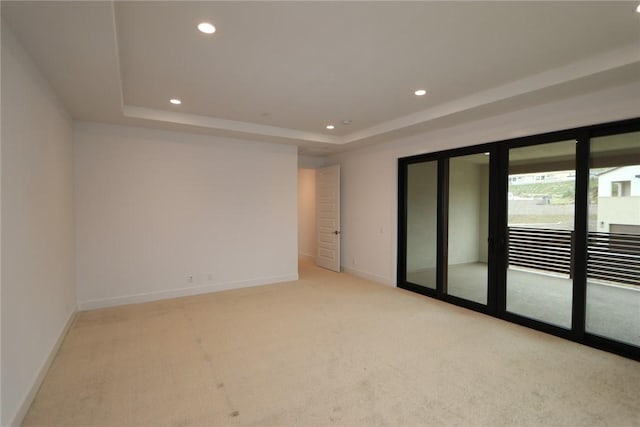 carpeted spare room featuring a tray ceiling