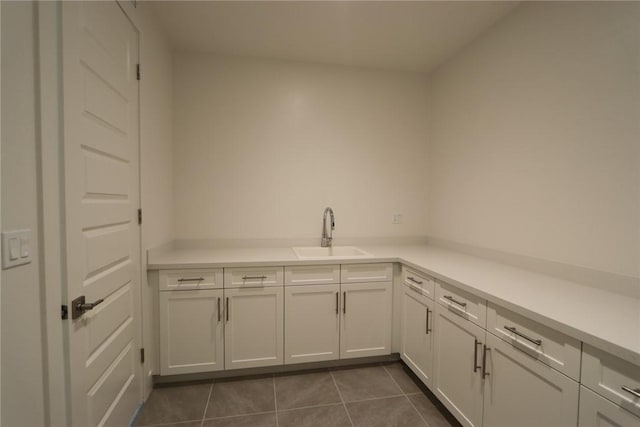 laundry area featuring sink and dark tile patterned floors