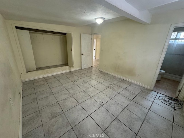 unfurnished bedroom with connected bathroom, a closet, and light tile patterned flooring