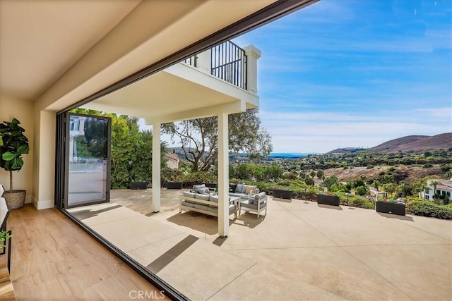 view of patio with a mountain view, a balcony, and an outdoor living space