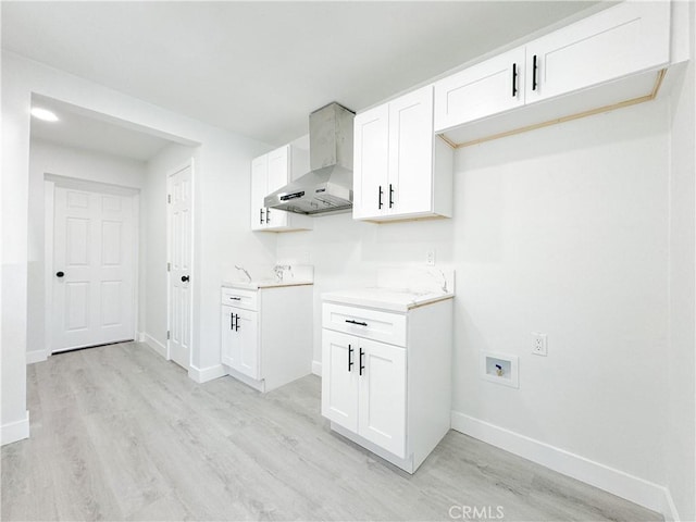 kitchen with wall chimney exhaust hood, light wood-type flooring, and white cabinetry