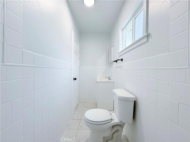 bathroom featuring tile patterned flooring, toilet, and tile walls