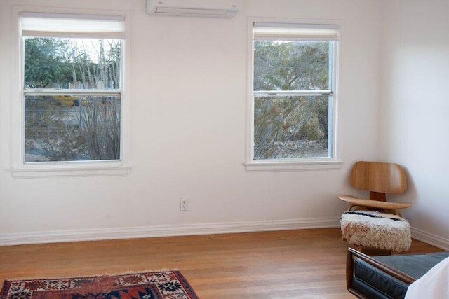 living area featuring a wall mounted air conditioner and light hardwood / wood-style flooring