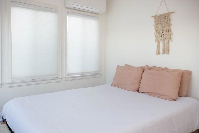 bedroom with a wall mounted air conditioner and multiple windows