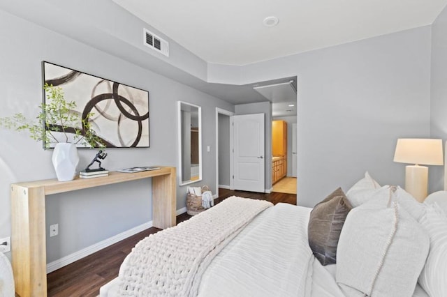 bedroom featuring ensuite bathroom and dark hardwood / wood-style floors