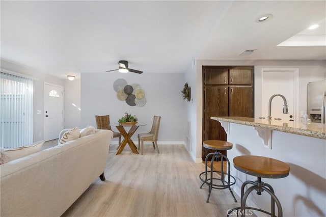 living room featuring ceiling fan, light wood-type flooring, and sink